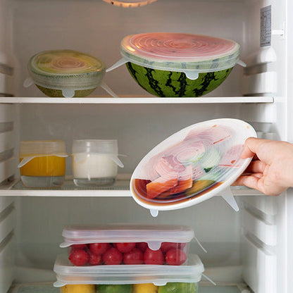 Hand opening a refrigerator door with a container of food inside.