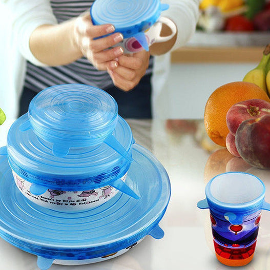 Blue silicone lid on a kitchen counter with colorful cups and fruits in the background