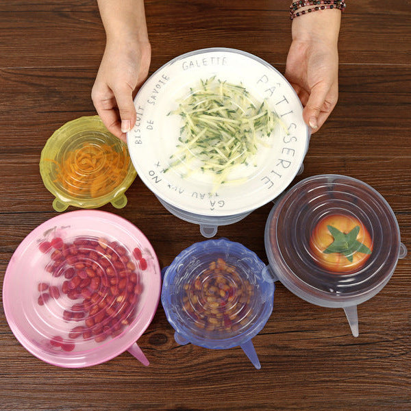Colorful silicone lids on bowls with food on a wooden surface
