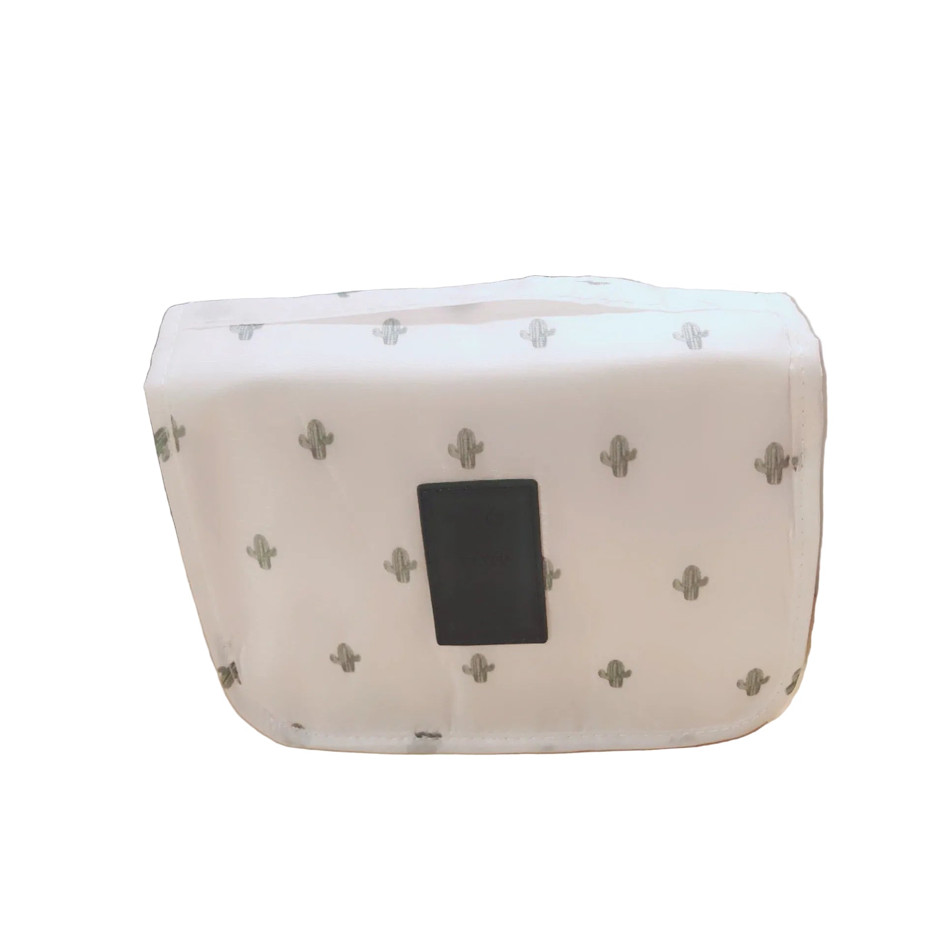 White pouch with black square on a beige surface with green plants in the background