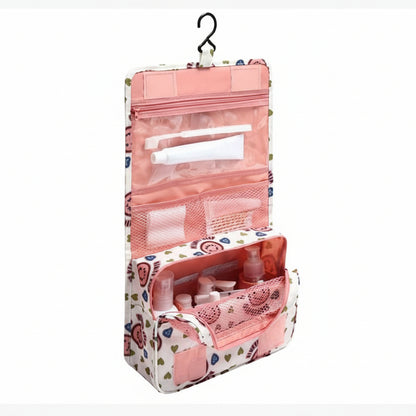 Pink floral hanging toiletry bag with cosmetic items on a white background