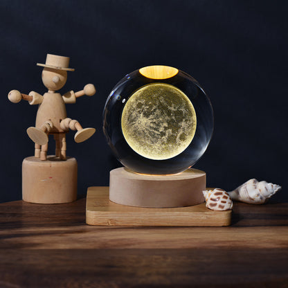 Wooden figure and crystal ball with moon design on a wooden stand against a dark background