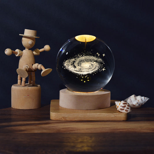 Wooden figure and galaxy-themed crystal ball on a wooden stand with a dark background