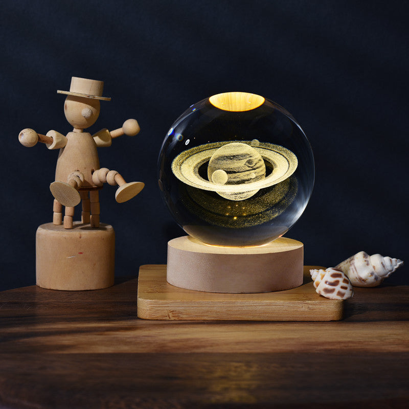 Wooden figure and crystal ball with Saturn model on a wooden stand against a dark background