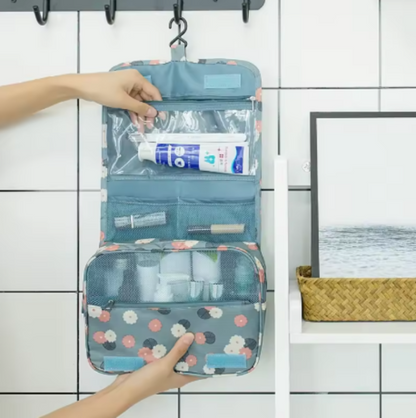 Person holding a Foldable Travel Toiletry Bag with cosmetic items against a tiled bathroom wall.