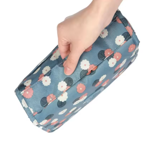 Hand holding a floral-patterned rectangular pouch against a white background